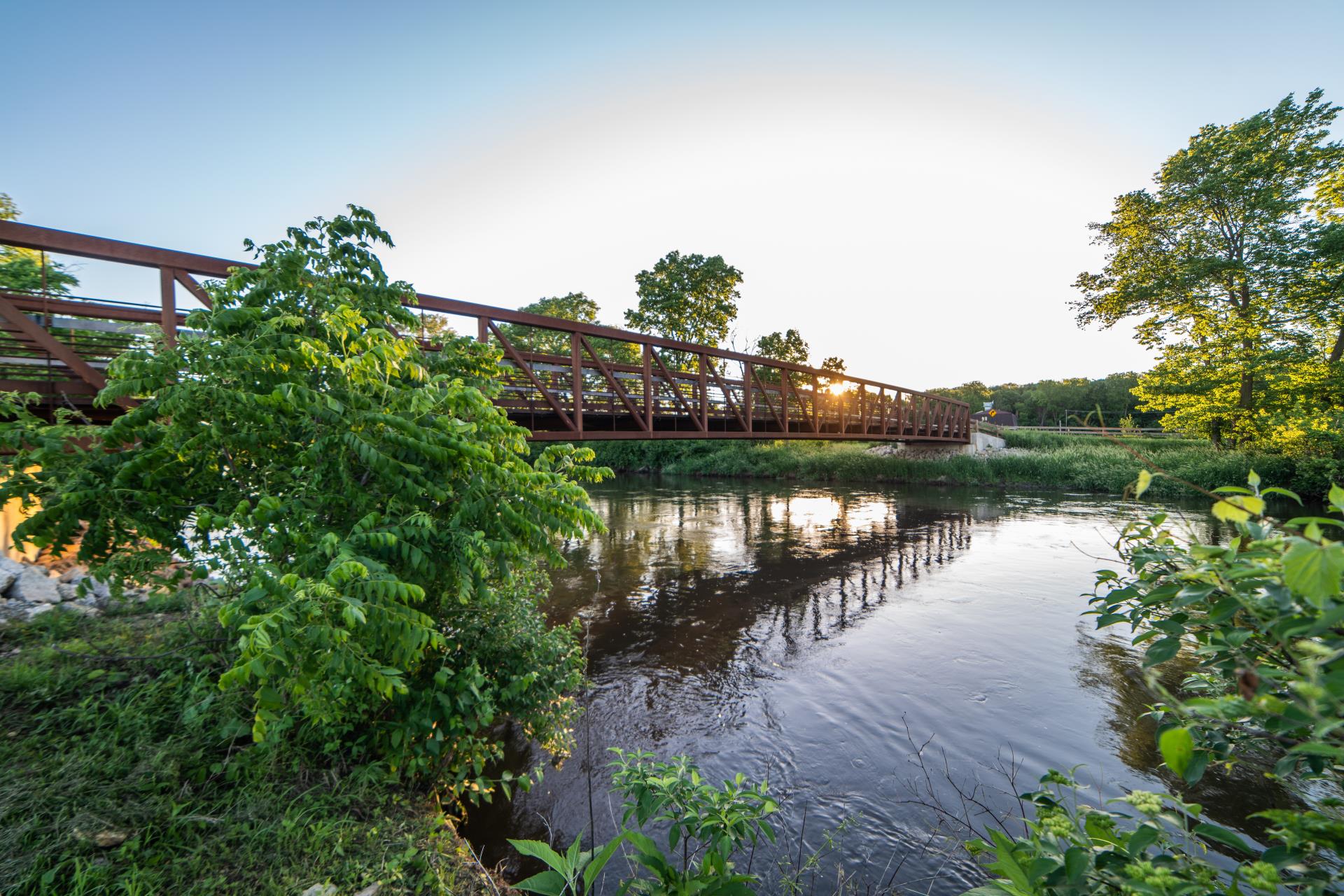 Bridge spanning the DuPage River in Plainfield Illinois with surrounding trees and calm water